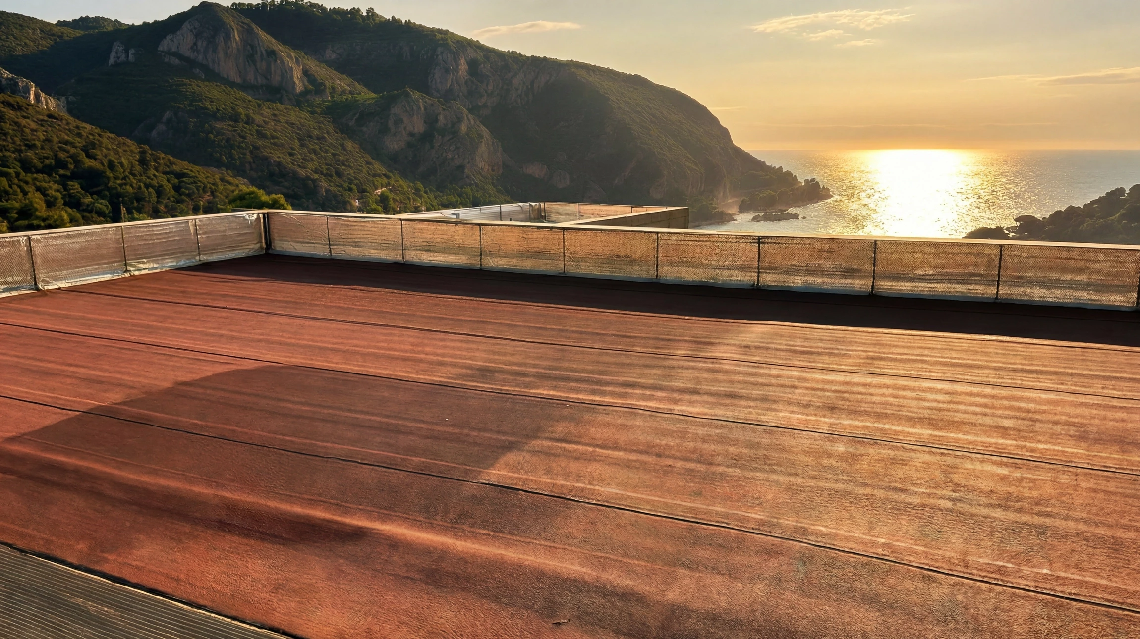 Terrasse en toiture avec revêtement de sol en lames de composite bois-polymère (WPC) teinte brun-rouge, garde-corps métallique avec brise-vue en filet
